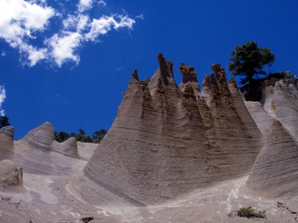 Formaciones rocosas erosionadas del Paisaje Lunar de Granadilla de Abona, en Tenerife, con cielo azul y vegetación dispersa