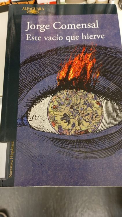Portada del libro Este vacío que hierve de Jorge Comensal, con ilustración de un ojo en llamas y símbolos cartográficos en la pupila