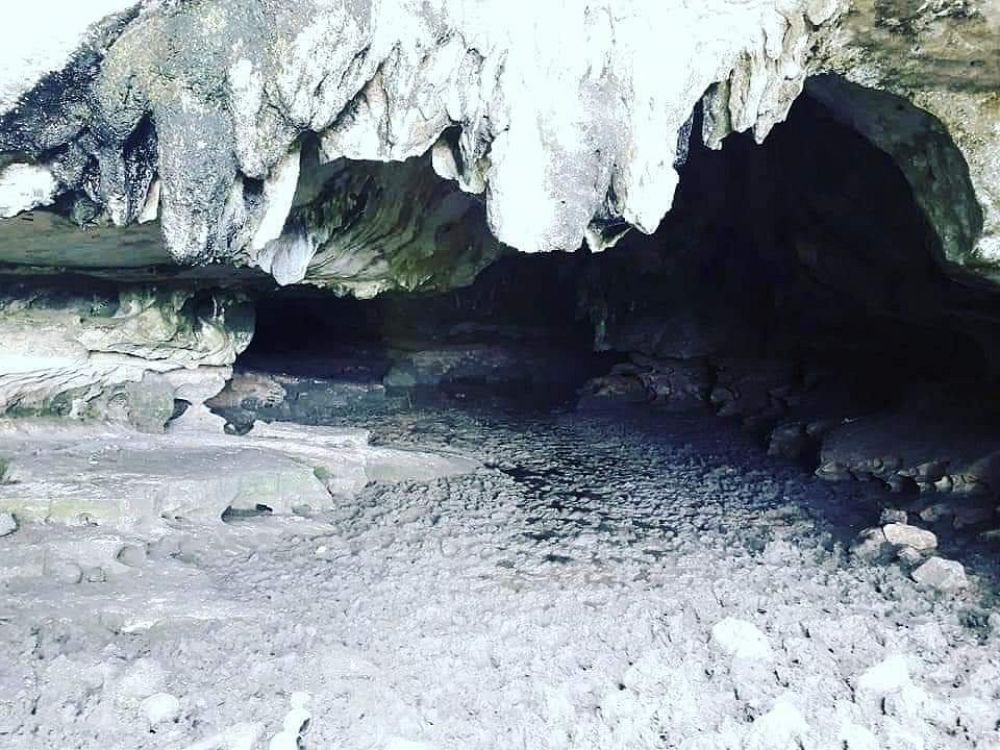 Mogotes de Jumagua Interior de una cueva en los Mogotes de Jumagua, con suelo rocoso y estalactitas visibles, iluminado parcialmente por luz natural
