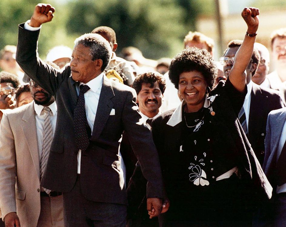 Mandela Nelson y Winnie Mandela caminan entre una multitud con el puño en alto, gesto de resistencia y poder político