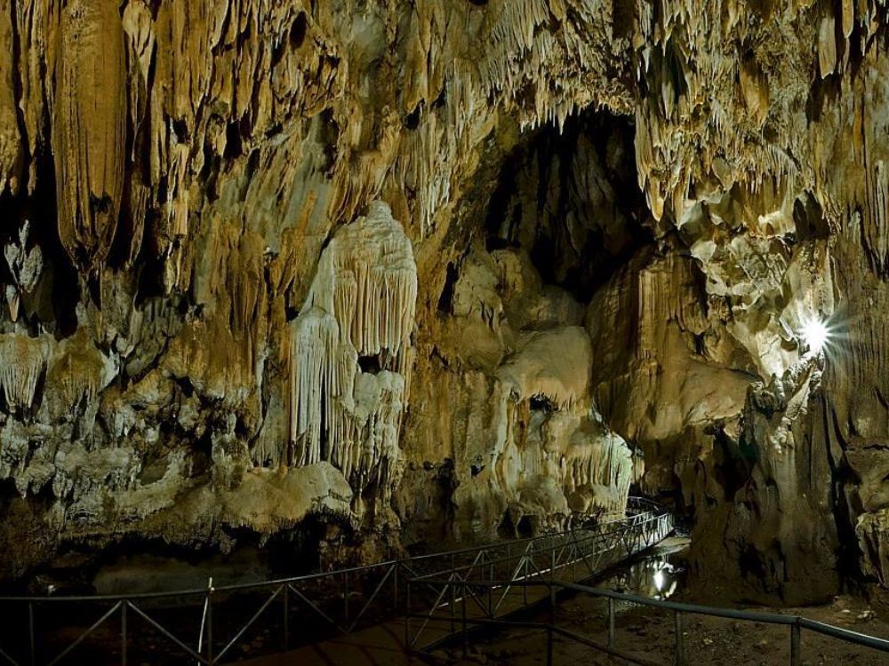 Interior de las Cuevas de Talgua con estalactitas, estalagmitas y pasarela metálica iluminada