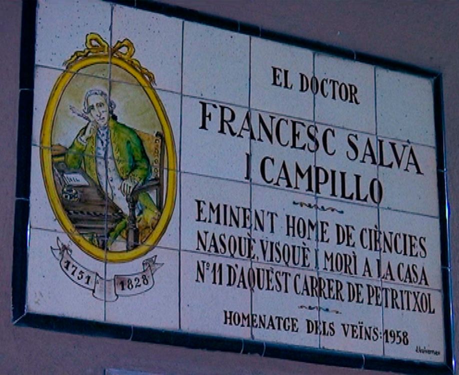 Placa cerámica conmemorativa en una pared, con un retrato ilustrado de Francisco Salvá y Campillo sentado ante una mesa y un texto que indica su nacimiento, vida y muerte en la calle Petritxol