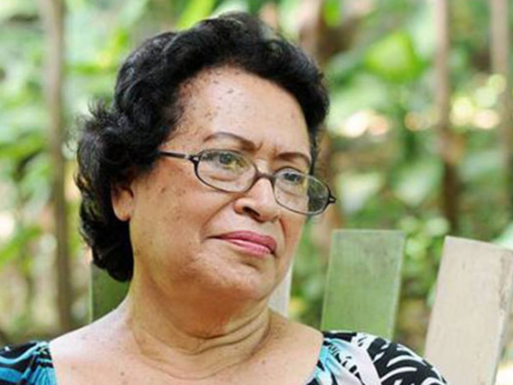 Ana Ilce Gómez 'Rostros del enigma'. Retrato de Ana Ilce Gómez sentada al aire libre, con gesto sereno y rodeada de vegetación