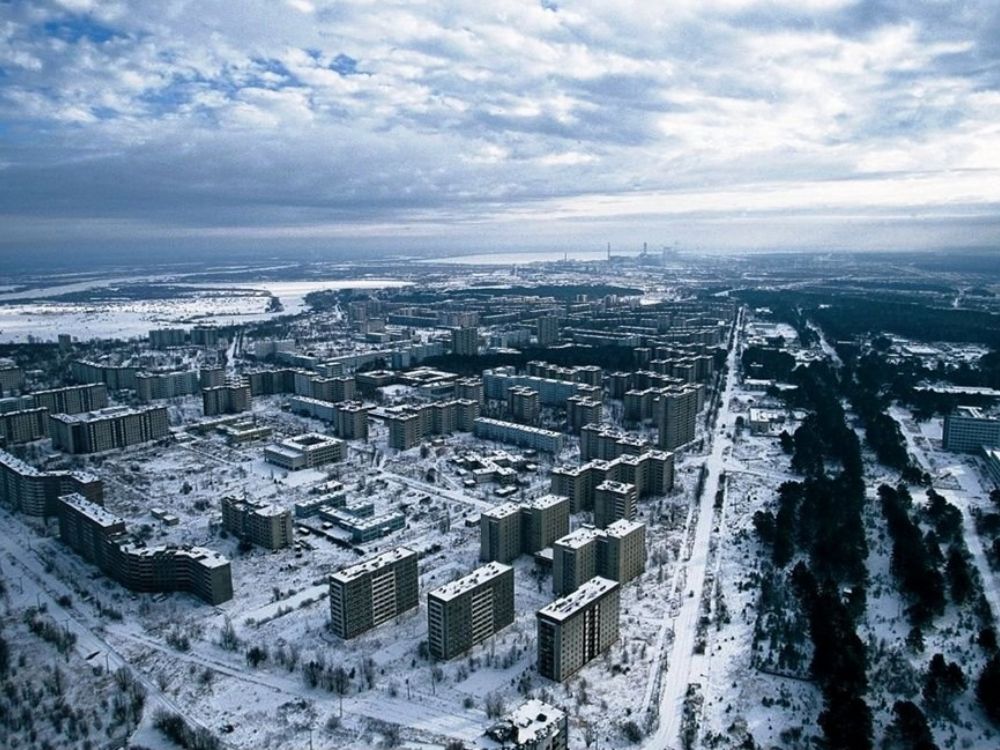 Vista aérea de la ciudad abandonada de Prípiat, con edificios residenciales ennegrecidos por el tiempo y un paisaje invernal que acentúa su estado de desolación