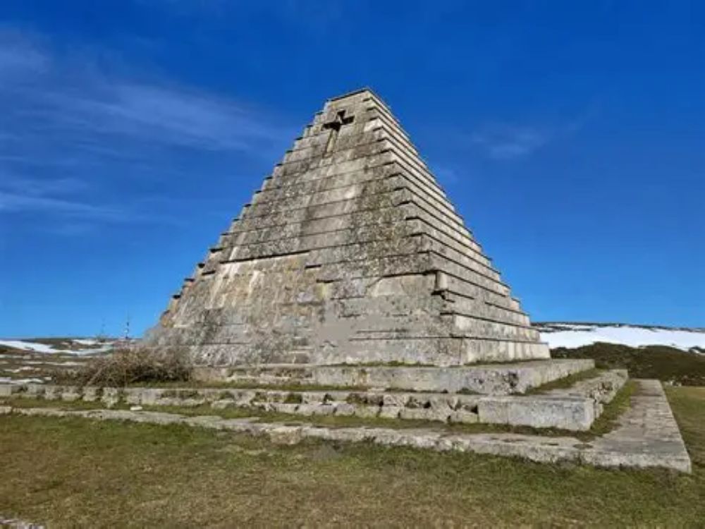 Pirámide de los Italianos en el Puerto del Escudo, estructura funeraria de piedra situada en un paisaje montañoso con nieve en las laderas