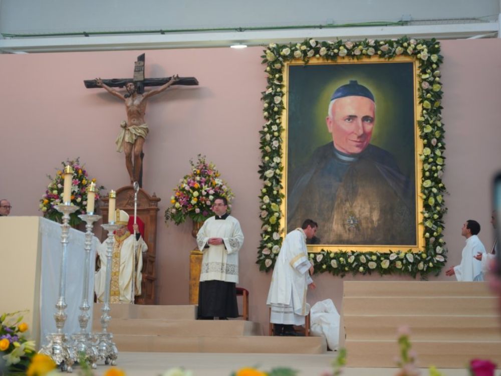 Ceremonia de beatificación de Salvador Valera, con un gran retrato del sacerdote rodeado de flores y varios obispos y sacerdotes celebrando la liturgia ante el altar